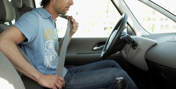 A man putting on seatbelt in a car