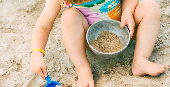 barn i sand som leker med bøtte og spade